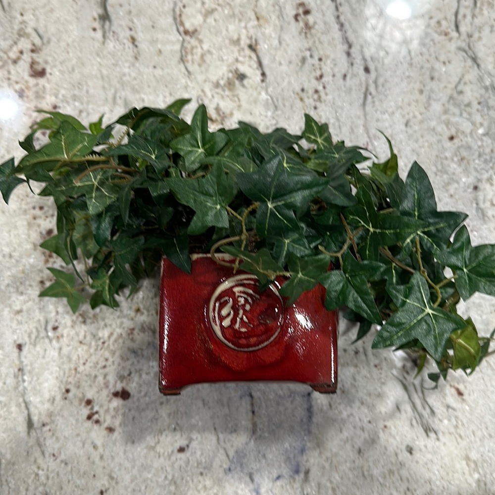 Decorative greenery arrangements in ceramic red pots.